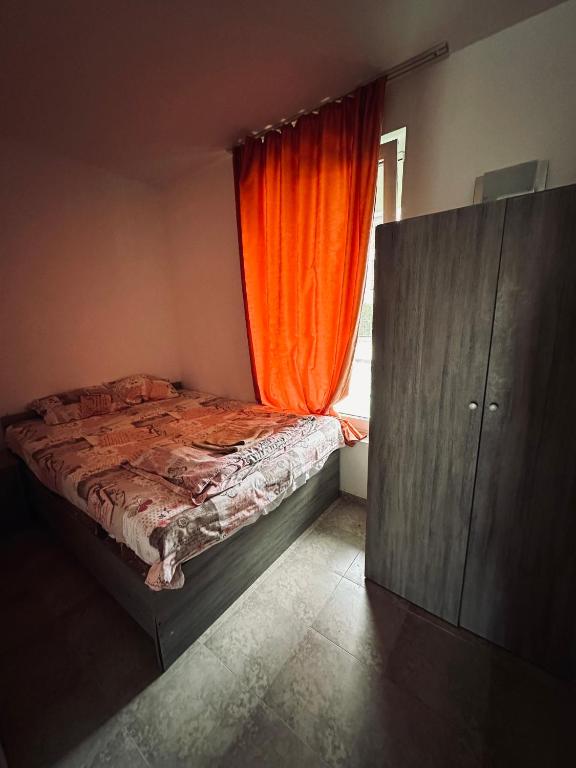 阳光海滩Stella Udacha Apartments & Studios的一间卧室配有一张带橙色窗帘的床