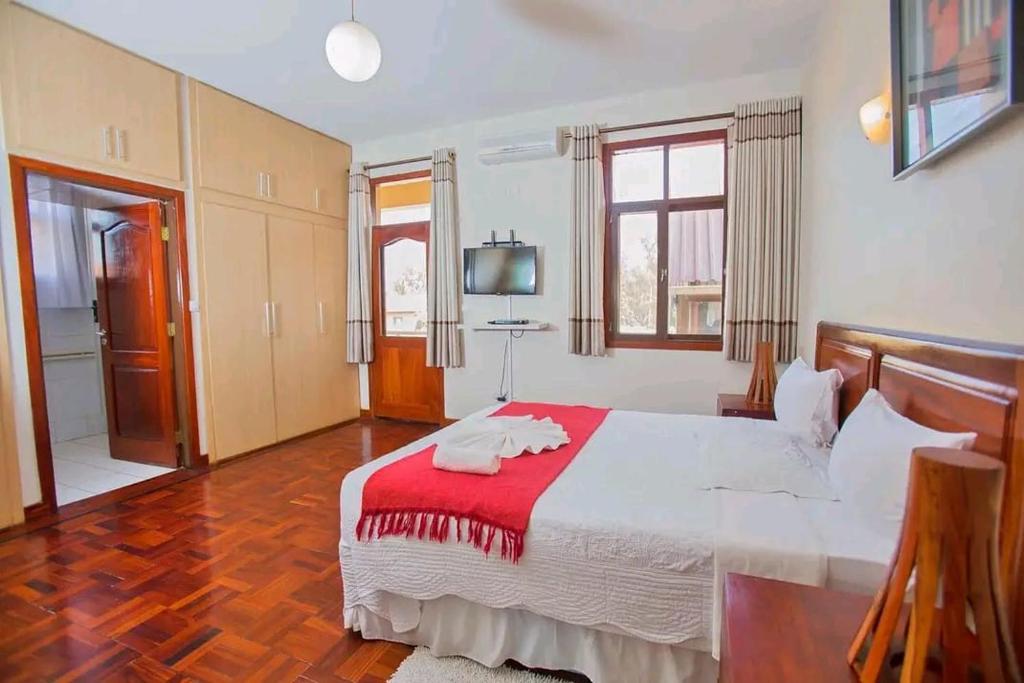 马普托Lidia's Place Guest House的一间卧室配有一张带红色毯子的大床