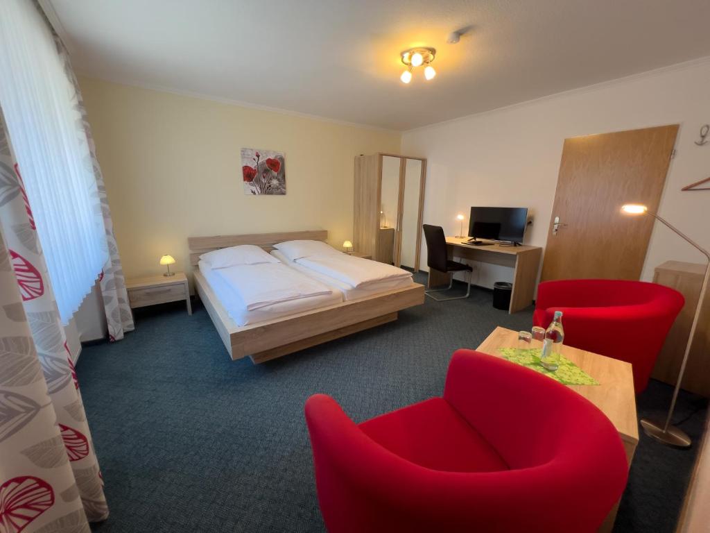 维林根Hotel Haus Christel的酒店客房,配有床铺和红色椅子