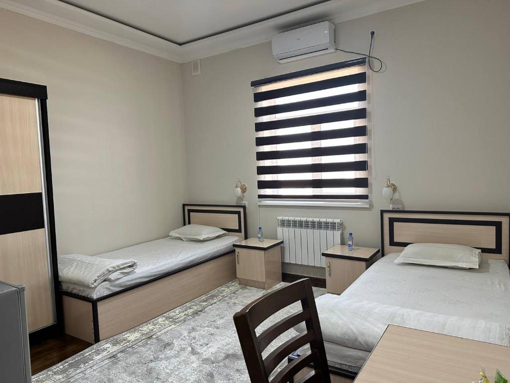 努库斯HOTEL ARAL的一间卧室设有两张床、一个窗口和一张桌子