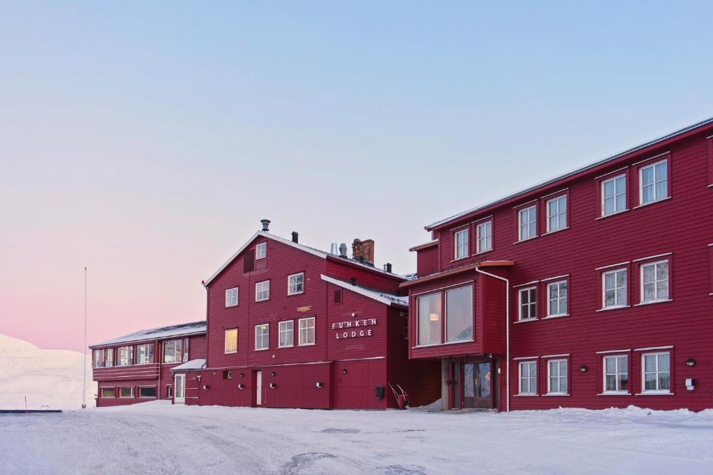 朗伊尔城方垦小屋酒店的前面有雪的红色建筑
