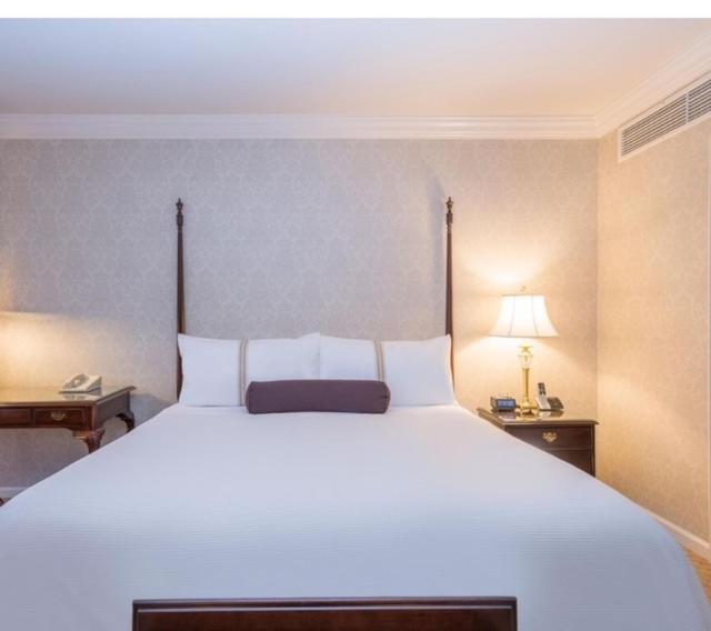 吉塞尼LA PLANETTE LODGE & BAR的卧室配有一张白色大床、两张桌子和一盏灯。