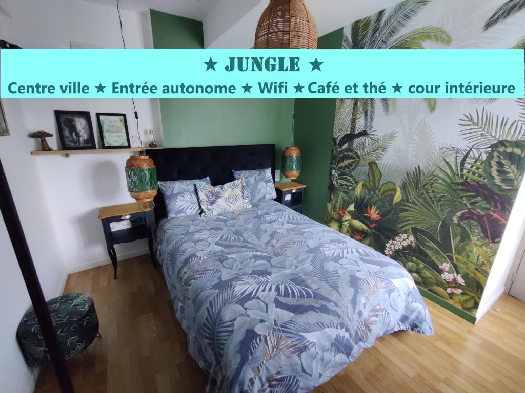 维特雷Appartement T2 "JUNGLE" Centre Ville de VITRÉ au calme coté cour的一间卧室配有一张带蓝色棉被的床