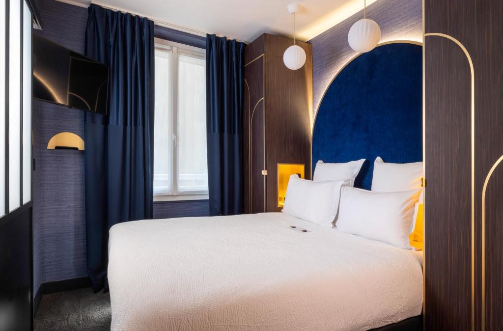 巴黎最佳西方布列塔尼蒙帕纳斯酒店的一间卧室配有一张大床和蓝色床头板
