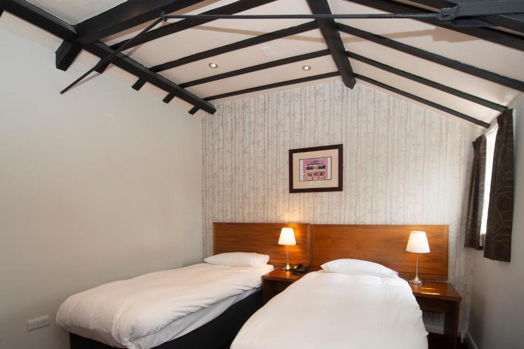 图克斯伯里霍普波勒沃德斯庞皇家酒店的配有白色墙壁和黑色横梁的客房内的两张床