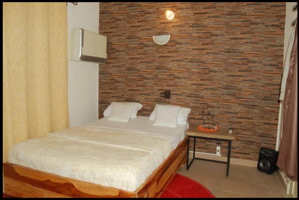 OuétoMaison d'hôte zouma的一间卧室设有一张床和砖墙