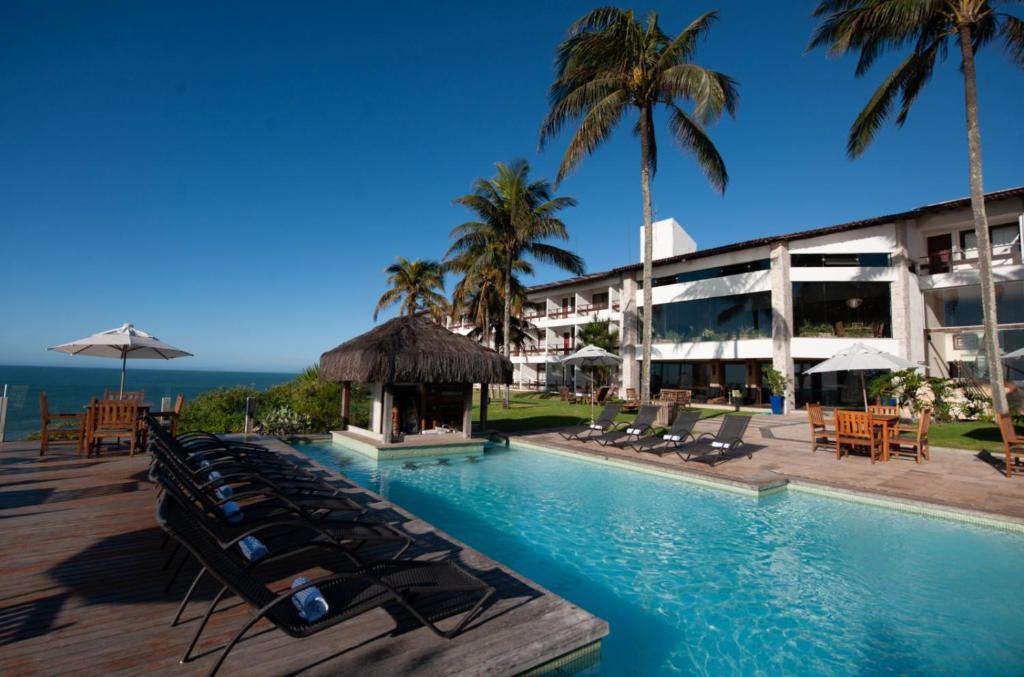 安谢塔Hotel Pontal de Ubu的一个带游泳池和椅子及棕榈树的度假村