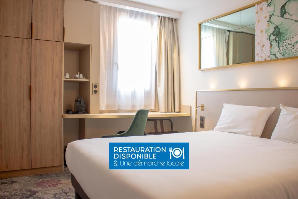 梅里尼亚克布里特酒店波尔多机场勒索雷泰尔店的酒店客房,配有床和镜子