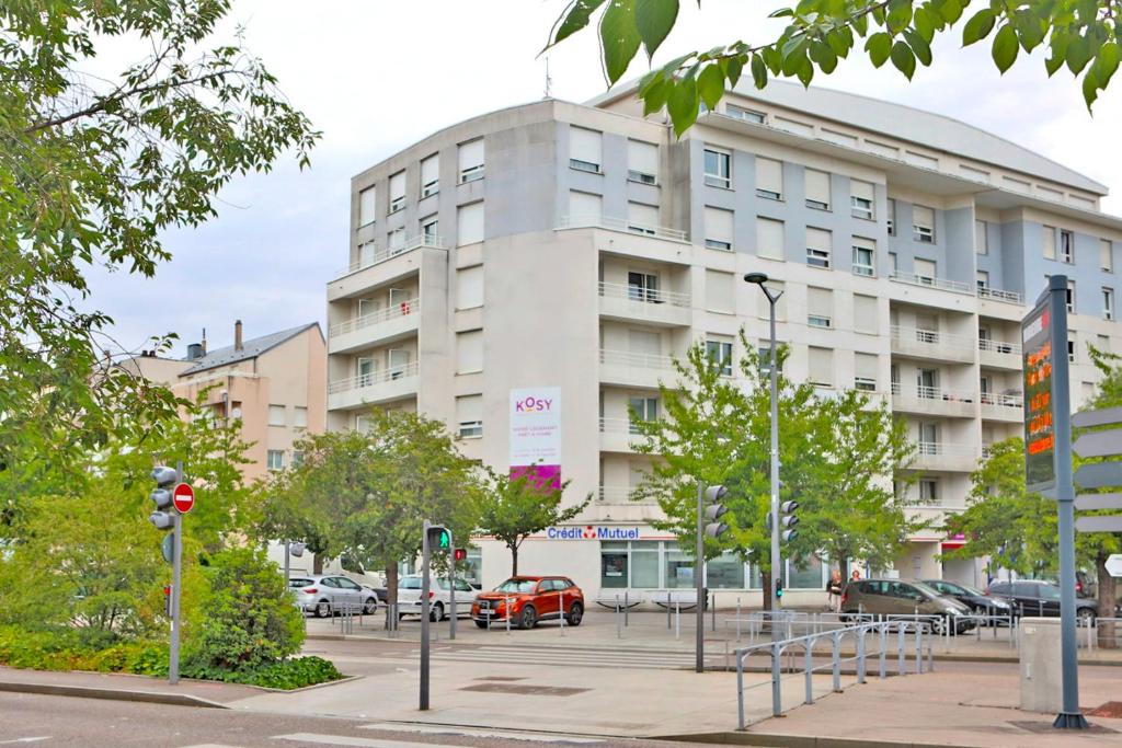 旺德夫尔莱南锡KOSY Appart'Hôtels - La Maison Des Chercheurs的一座白色的大建筑,前面有汽车停放