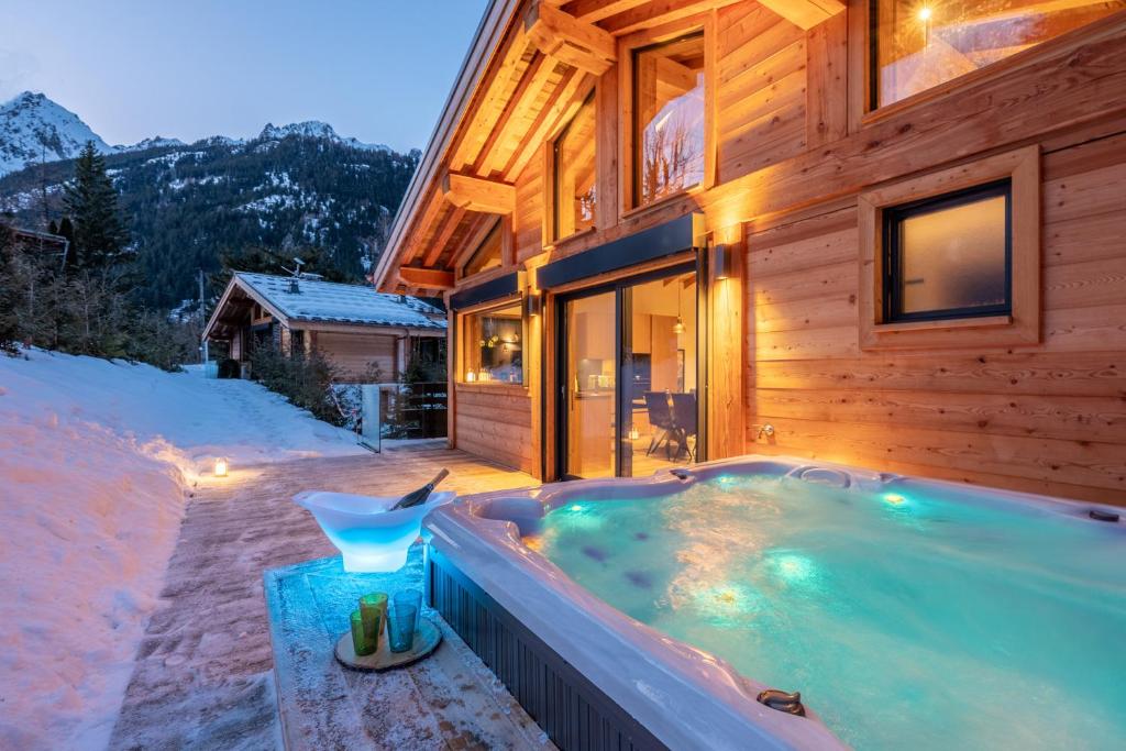 夏蒙尼-勃朗峰Chalet Seven Summits - Pool - Sauna - Jacuzzi的雪中房子前面的热水浴池