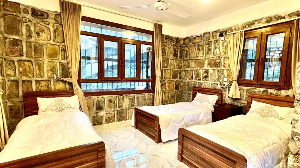 Bilād SaytGuest house baldsayt的一间卧室设有两张床和石墙