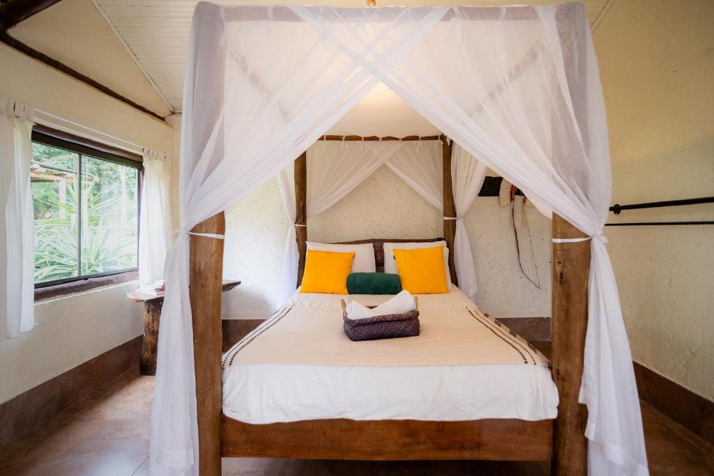 布鲁马迪纽Ecovila Coração da Mata的一间卧室配有天蓬床,提供黄色和橙色枕头