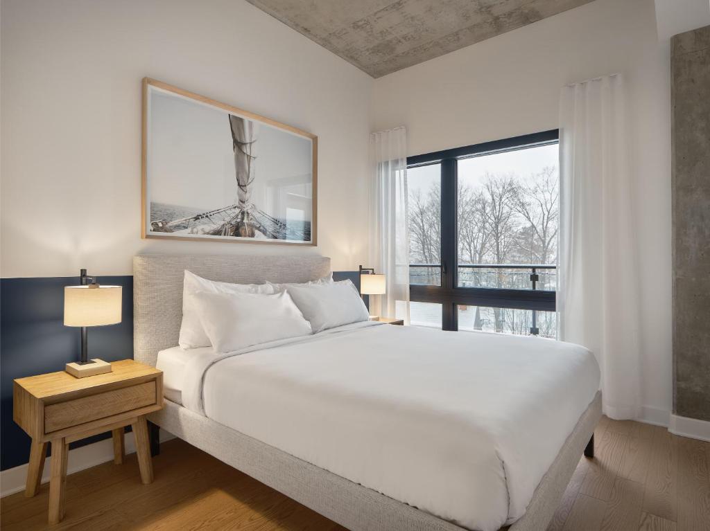 梅戈格Hôtel - Expérience - Quartier Des Marinas的白色的卧室设有一张大床和一个窗户