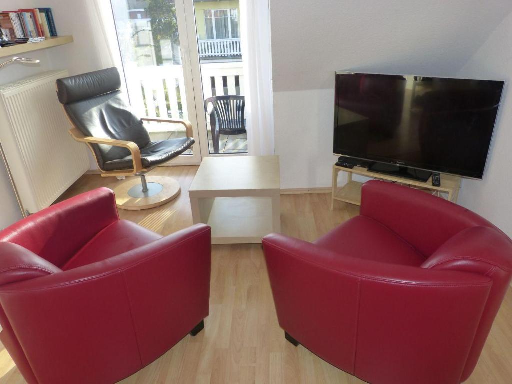 奥斯赛拜-屈隆斯博恩Strandschloesschen-Haus-II-WE-23-9743的客厅配有2把红色椅子和平面电视