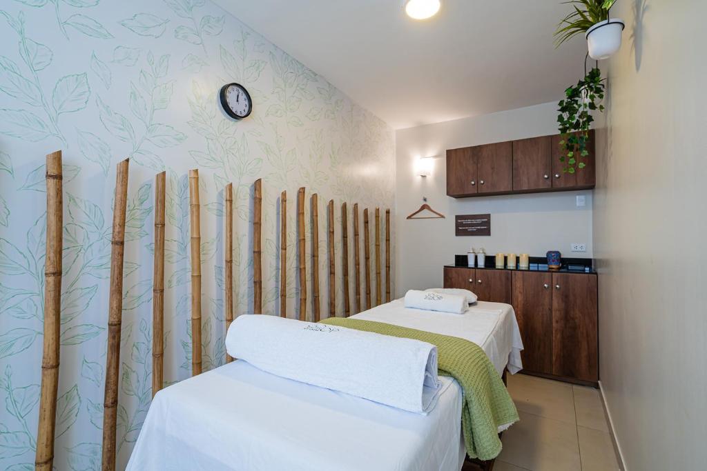 特鲁希略Casa Andina Standard Trujillo Plaza的客房设有两张床和带时钟的墙壁。
