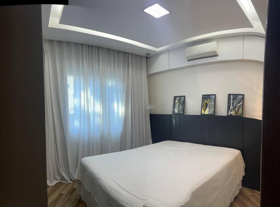 贝洛奥里藏特Casa Aconchegante的卧室配有白色的床和窗户。