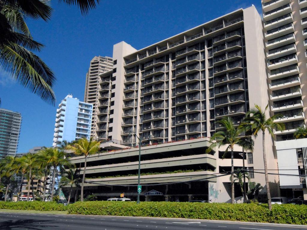 檀香山威基基阿瓜棕榈酒店的一座高大的建筑,前面有棕榈树