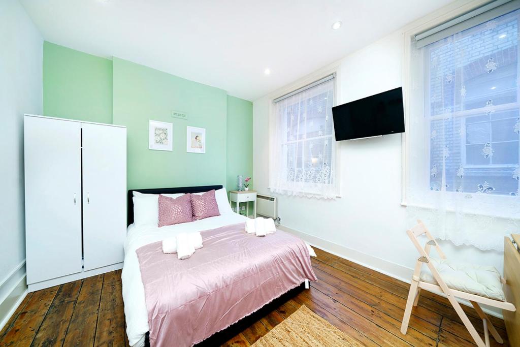 伦敦Brewer Street Central Apartments的一间卧室配有一张带粉色床单的床和一台电视。