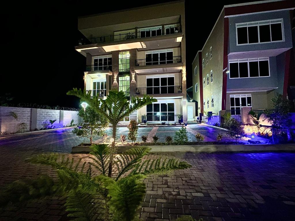 坎帕拉Amy Luxury Apartments In Munyonyo的一座在晚上有棕榈树的建筑