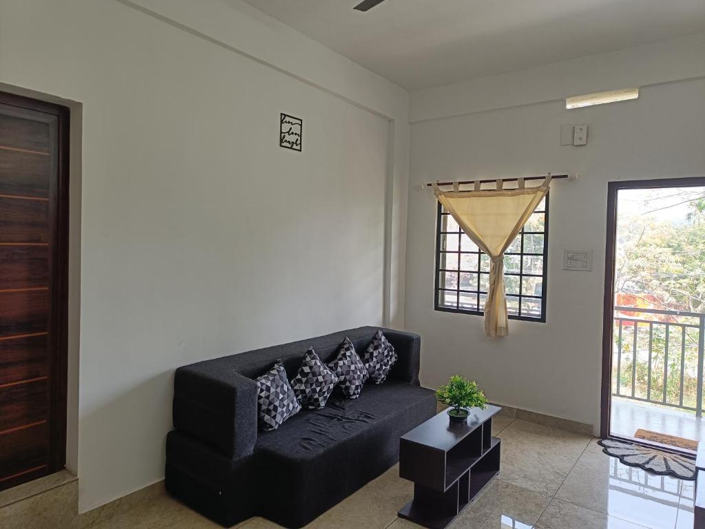 玛莱尤尔Bliss Villa 2 bedroom Apartment Marayoor的客厅里一张黑色沙发,设有窗户
