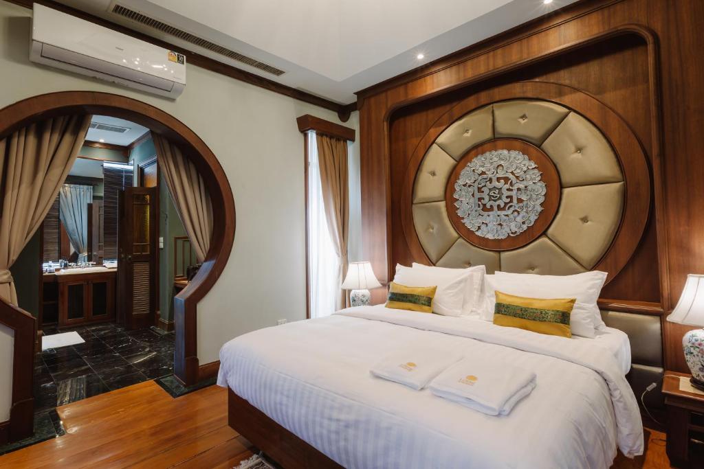 清迈Lunar Mansion Hotel的卧室配有一张白色大床和木制床头板