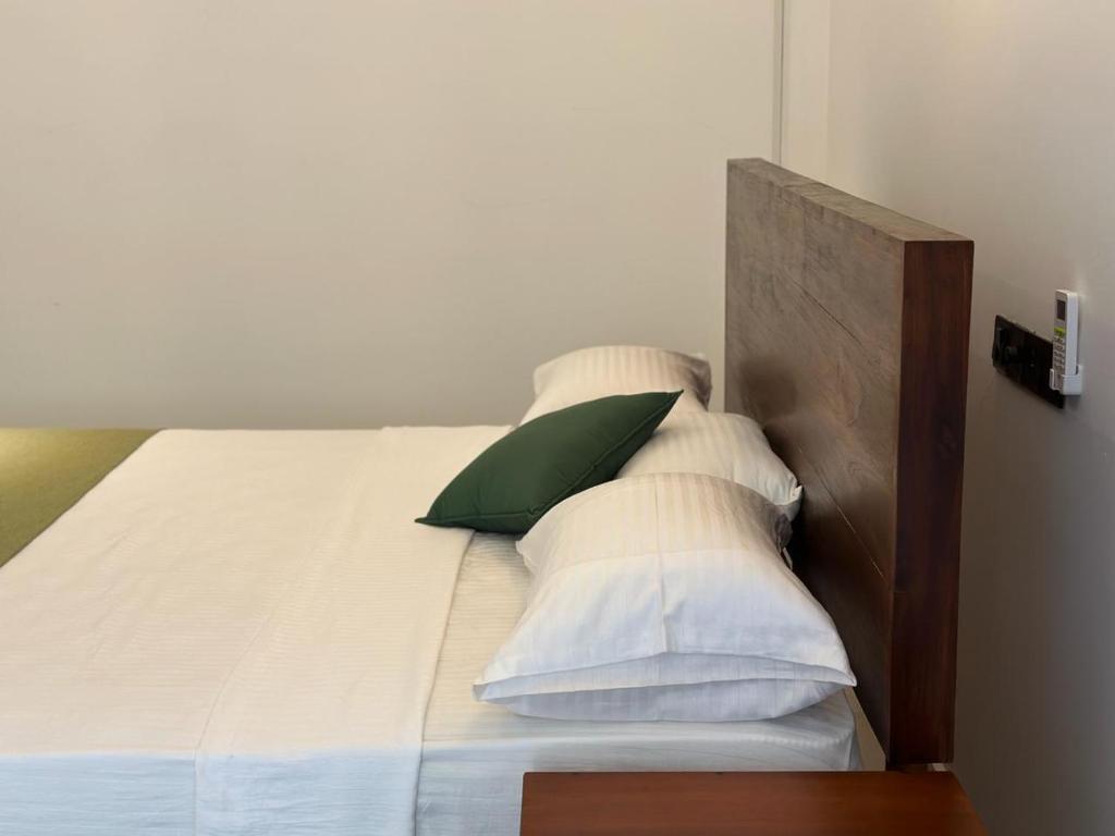 阿努拉德普勒Emerald Home Stay的一张带白色枕头和绿色枕头的床