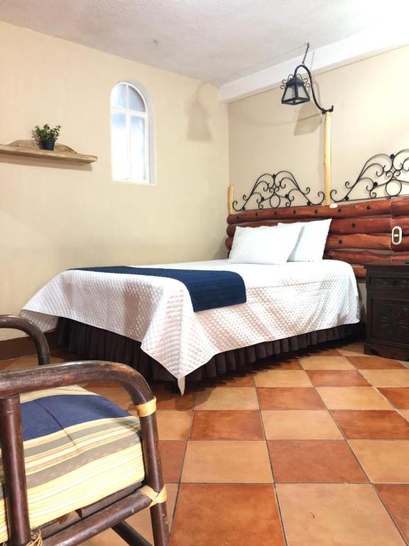 特克潘危地马拉Casa de los Abuelos Hotel的一间卧室配有一张床和一把椅子