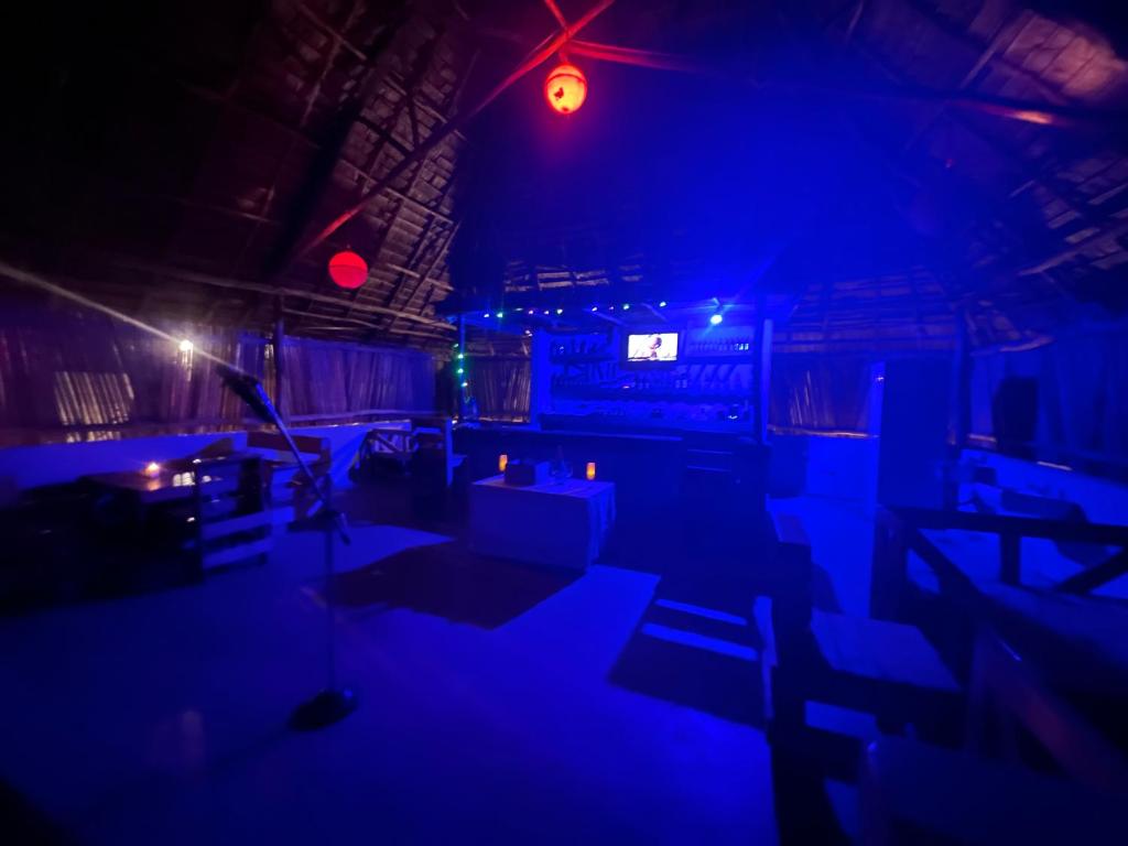基林多尼New Dindini Lodge的一间设有蓝色灯光和桌椅的黑暗客房