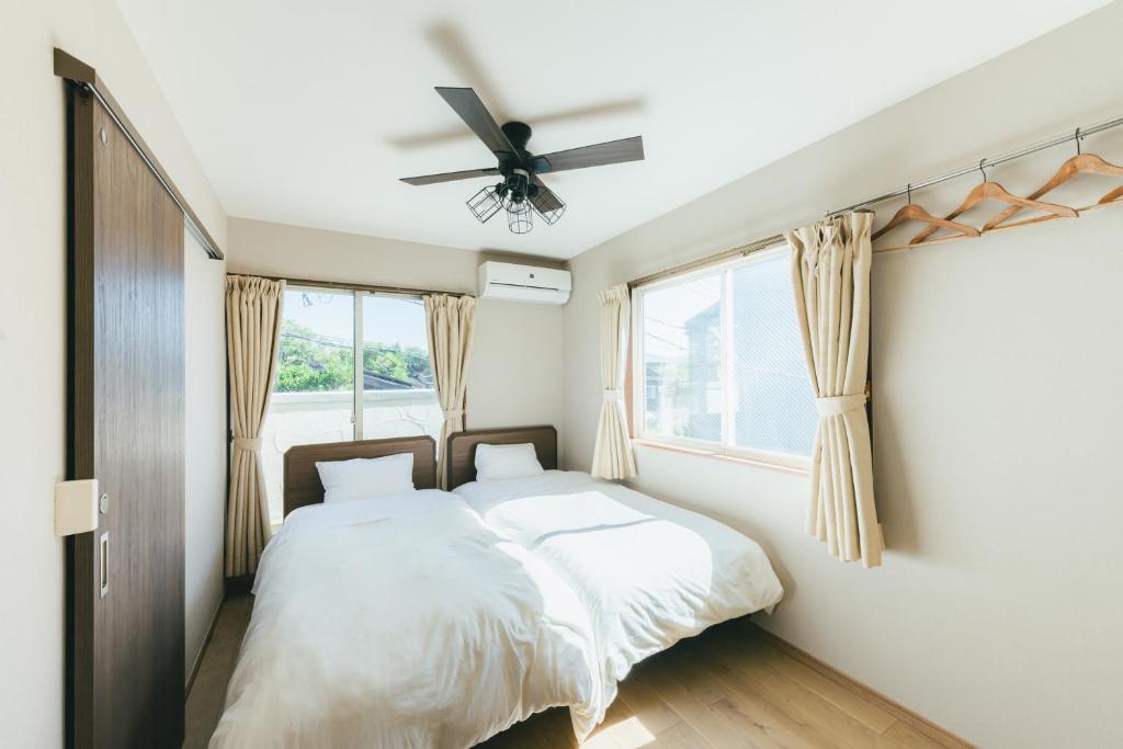 镰仓市十八甫旅馆的一间卧室配有两张床和吊扇