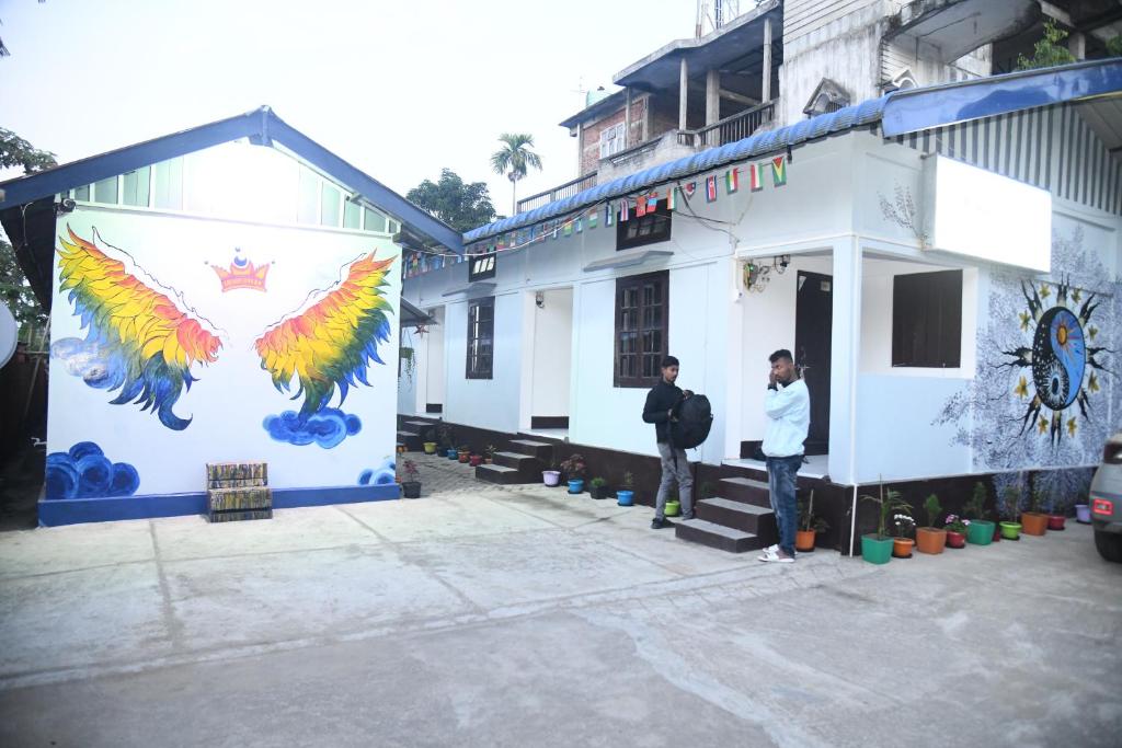 GolāghātKaameng Guest House的两个人站在一座壁画建筑前面