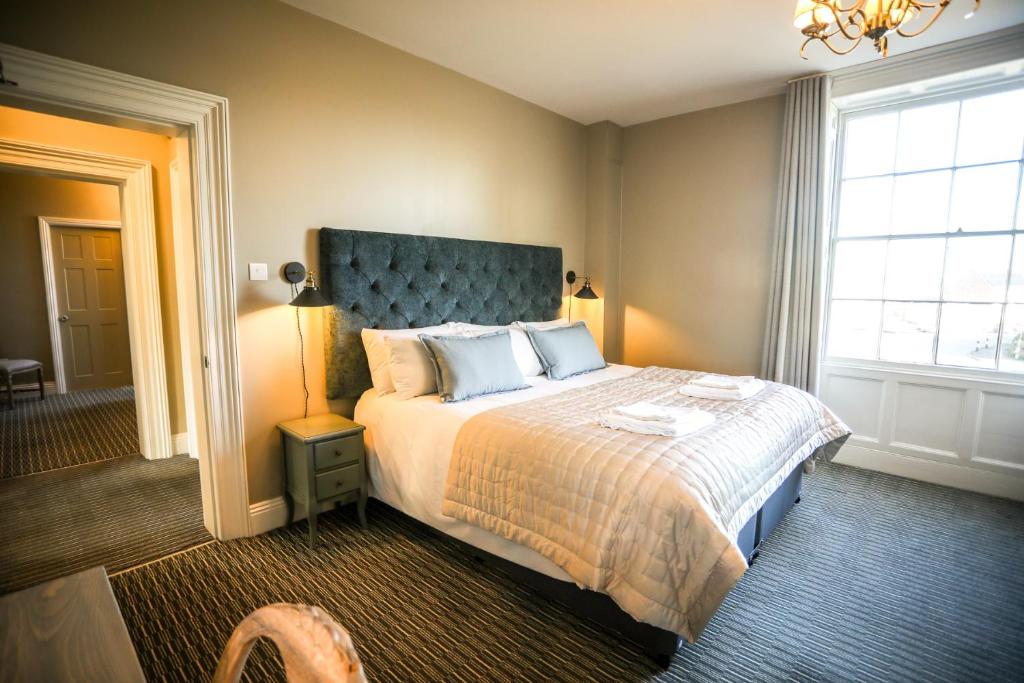 斯通豪斯The Lazy Goose - Coffee House & Bedrooms的一间卧室配有一张大床和蓝色床头板