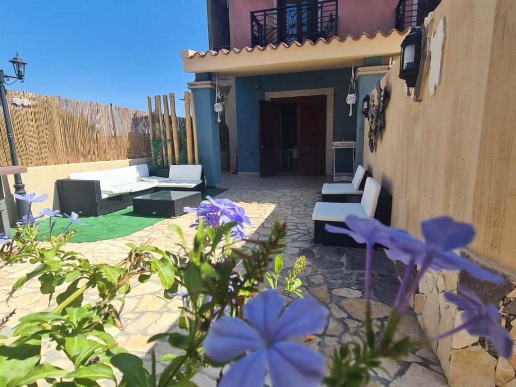 维拉西米乌斯Ohana Blue House的庭院配有白色家具和紫色鲜花