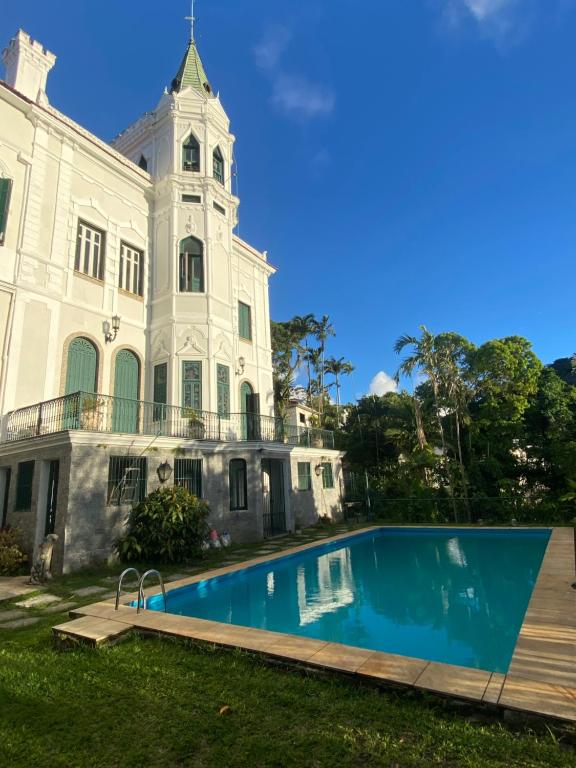 里约热内卢Castelo dos Tucanos Hostel的一座白色的大建筑,前面设有一个游泳池