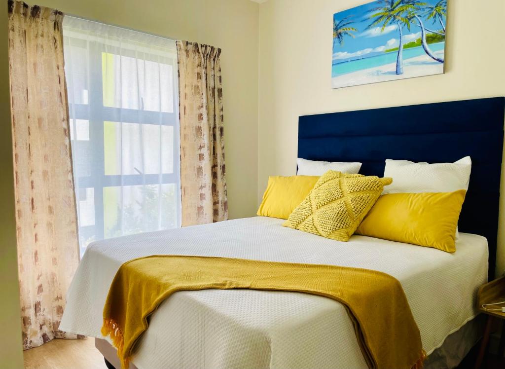 约翰内斯堡2 Bedroom 2 Bathroom Apartment in Sandton的一间卧室配有一张带黄色枕头的床和一扇窗户