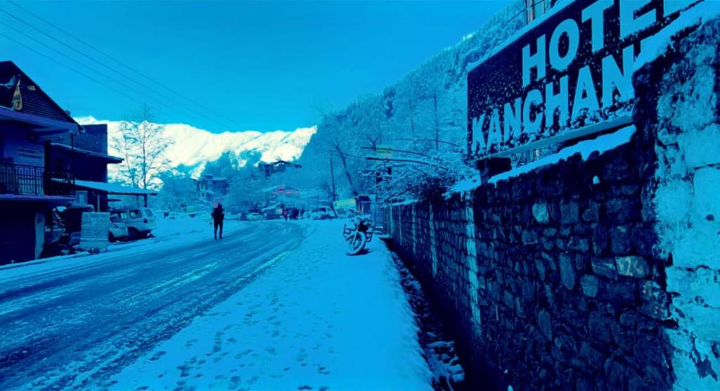 马拉里Hotel Kanchani - A Majestic Mountain Retreat的沿着建筑物旁的雪覆盖的街道行走的人