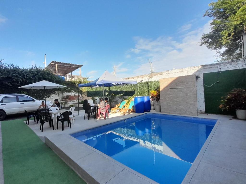 曼塔HOSTAL SAN MARINO的后院的游泳池,配有桌椅