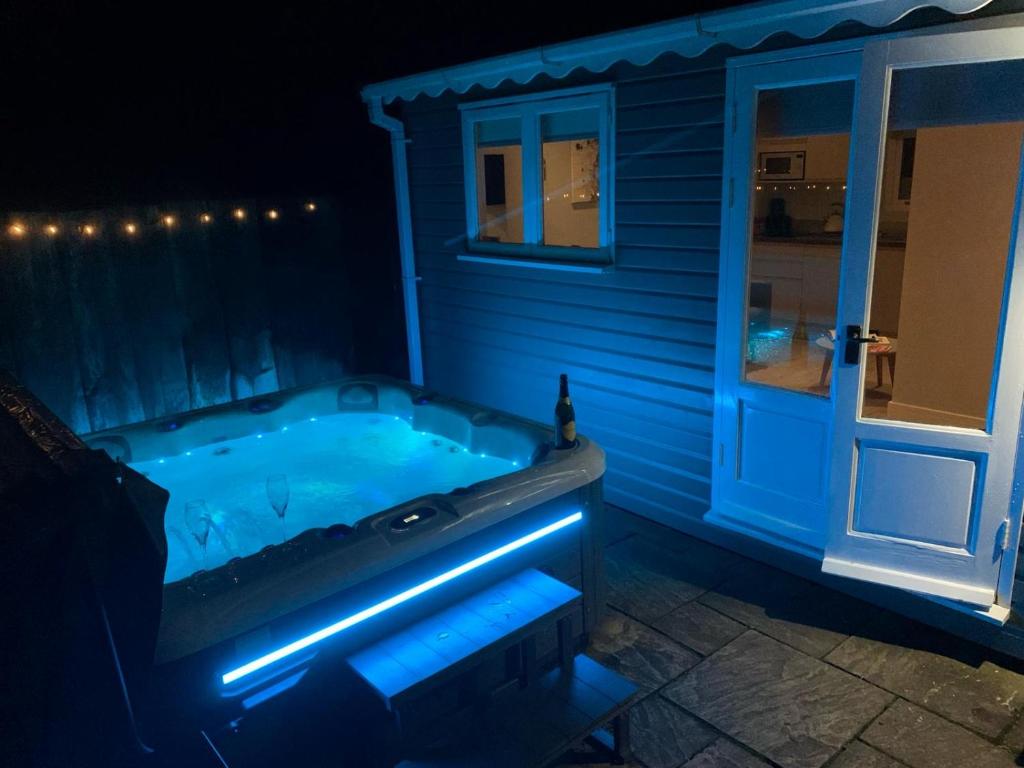 布里奇诺斯The Summerhouse, countryside retreat with private hot tub的蓝色灯光的房子里设有一个按摩浴缸
