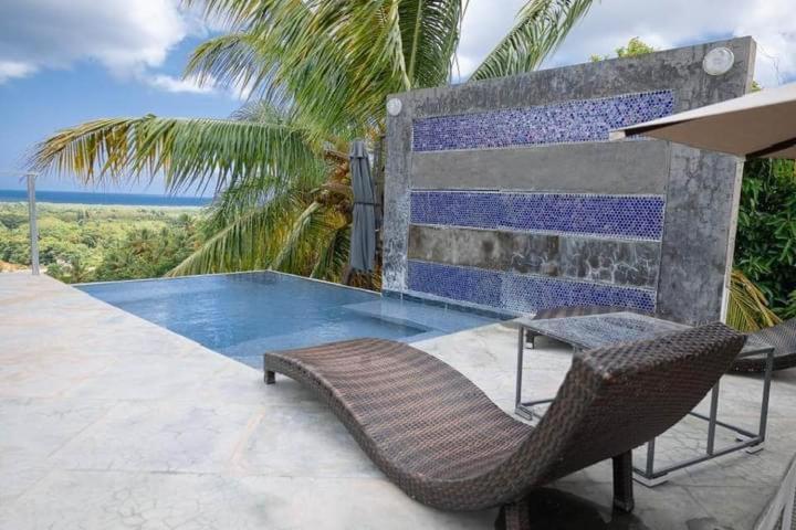 里奥圣胡安Villa-Fede 4 habitaciones en Rio San Juan的游泳池旁的藤椅