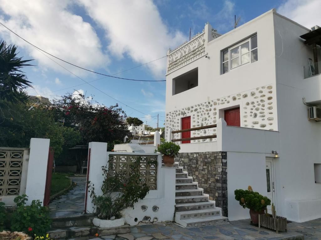 米克诺斯城VILLA VASILIS ORNOS的白色的房子,有红色的门和楼梯