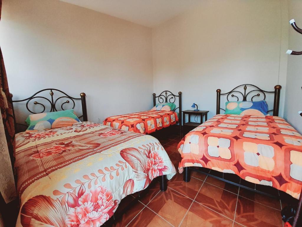 TorotoroHospedaje Matita - Torotoro的一间卧室配有两张带橙色棉被的床
