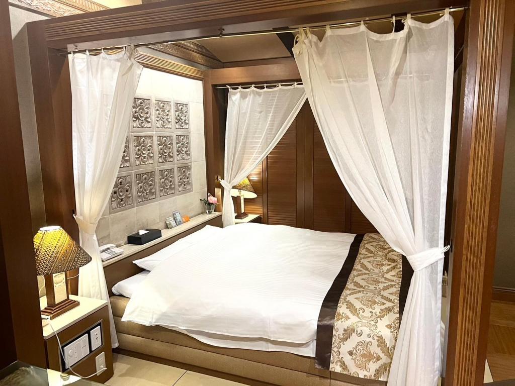 神户Hotel Pareo (Adult Only)的一间卧室配有带窗帘的天蓬床