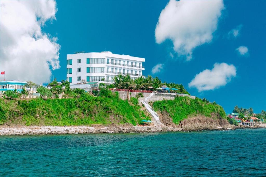 惹岛Ly Son Pearl Island Hotel & Resort的水边小山上的白色建筑