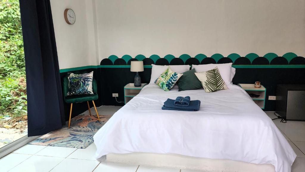 象岛Easy Life Koh Chang的一间卧室配有一张白色床和绿色床头板