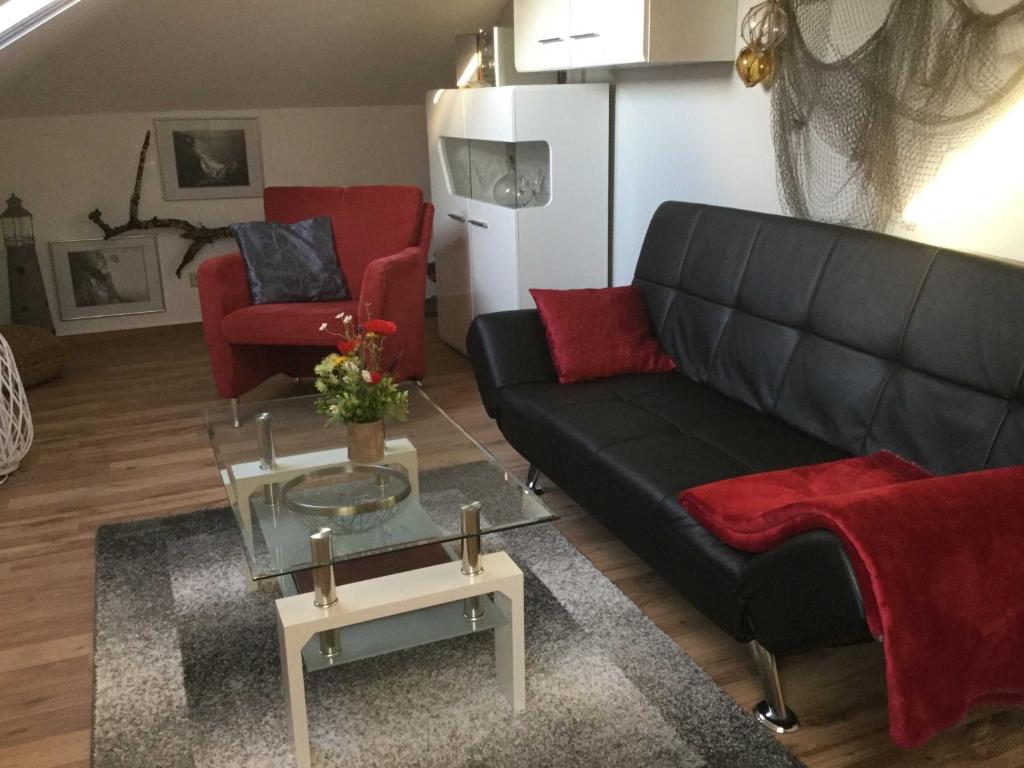 宾茨FeWo Tinchen Prora Ruegen的客厅配有黑色沙发和红色椅子