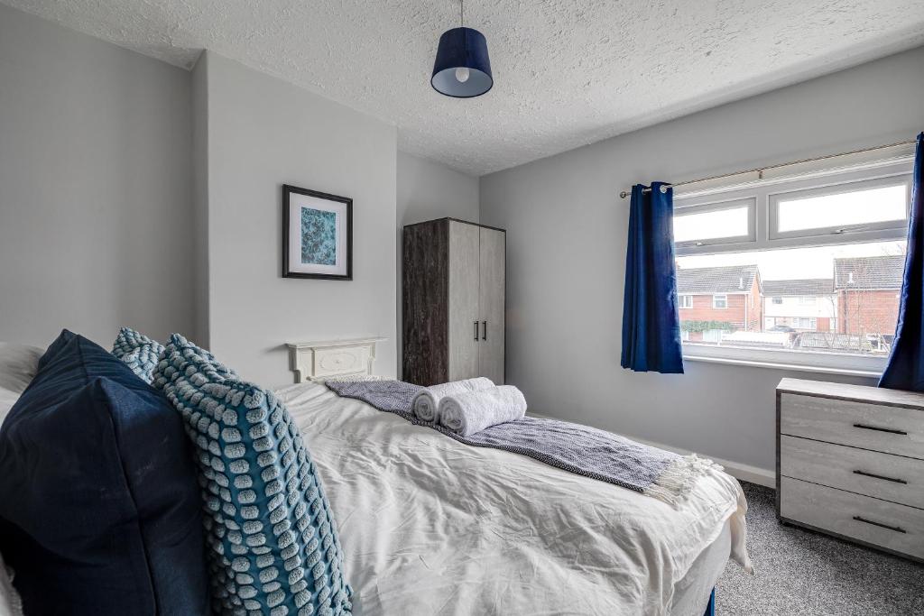 克鲁Contract workers, Professionals, Families, Parking的一间卧室配有一张带蓝色枕头的床和一扇窗户。