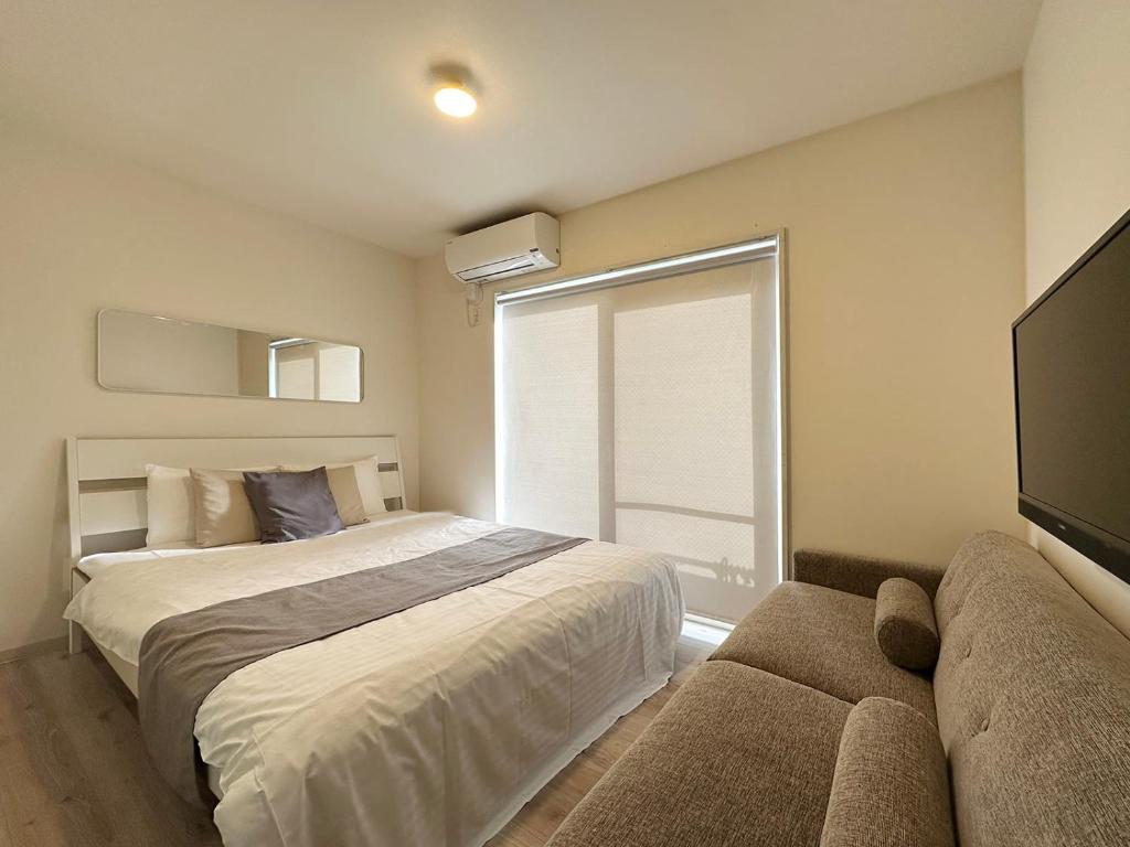 尾道市bHOTEL Yutori - Cozy 1Br Apartment for 3Ppl in Onomichi City的一间卧室设有床、窗户和沙发