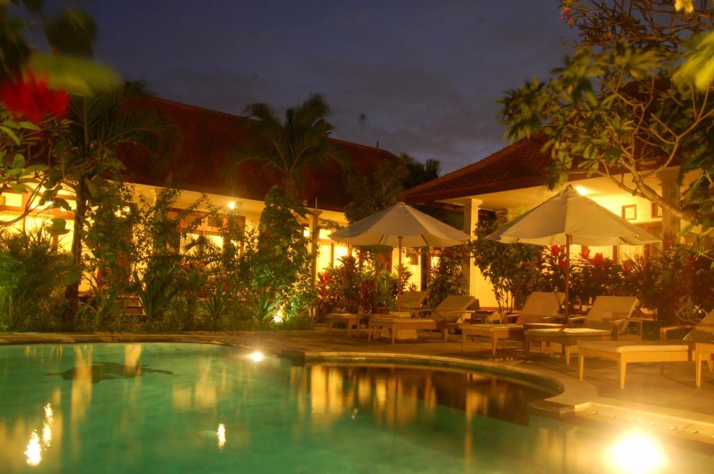沙努尔格鲁卡亚民宿的一个带椅子和遮阳伞的游泳池的度假酒店