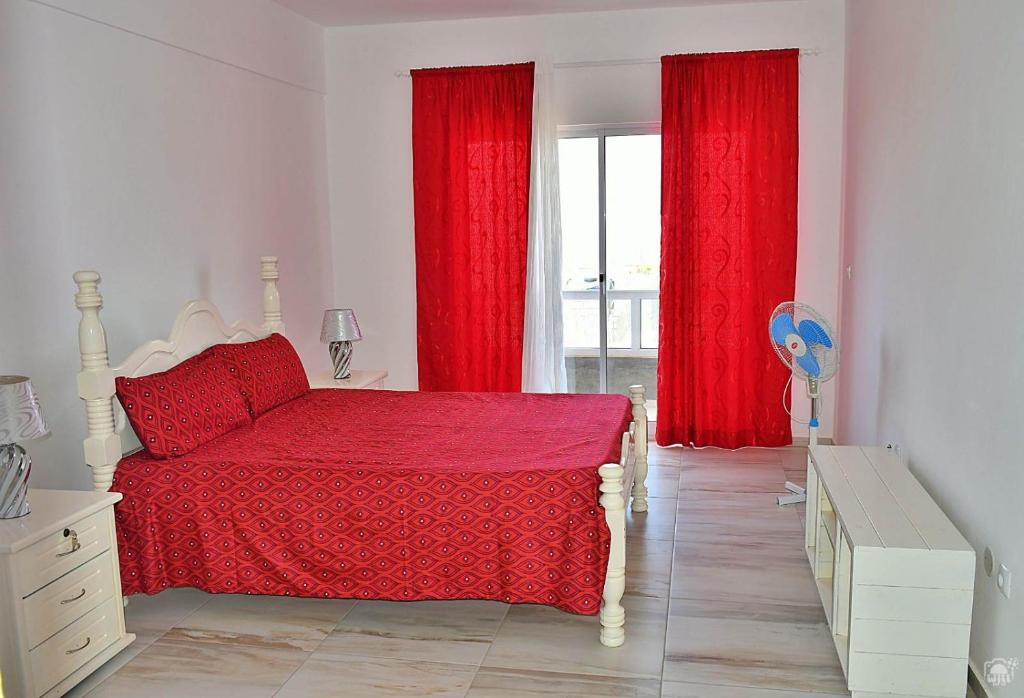 TarrafalTARRAFAL SN TOUR的一间卧室配有红色窗帘、一张床和窗户