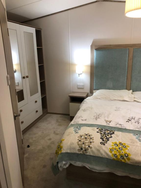 坦伯利Lovely Caravan的一间卧室配有一张床、梳妆台和衣柜。