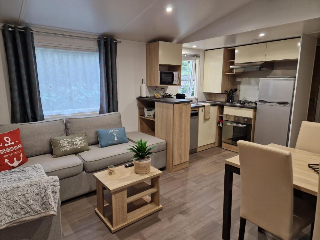 圣布里文莱丝皮恩Mobil home tout confort 3 chambres camping Les Pierres Couchées的带沙发的客厅和厨房